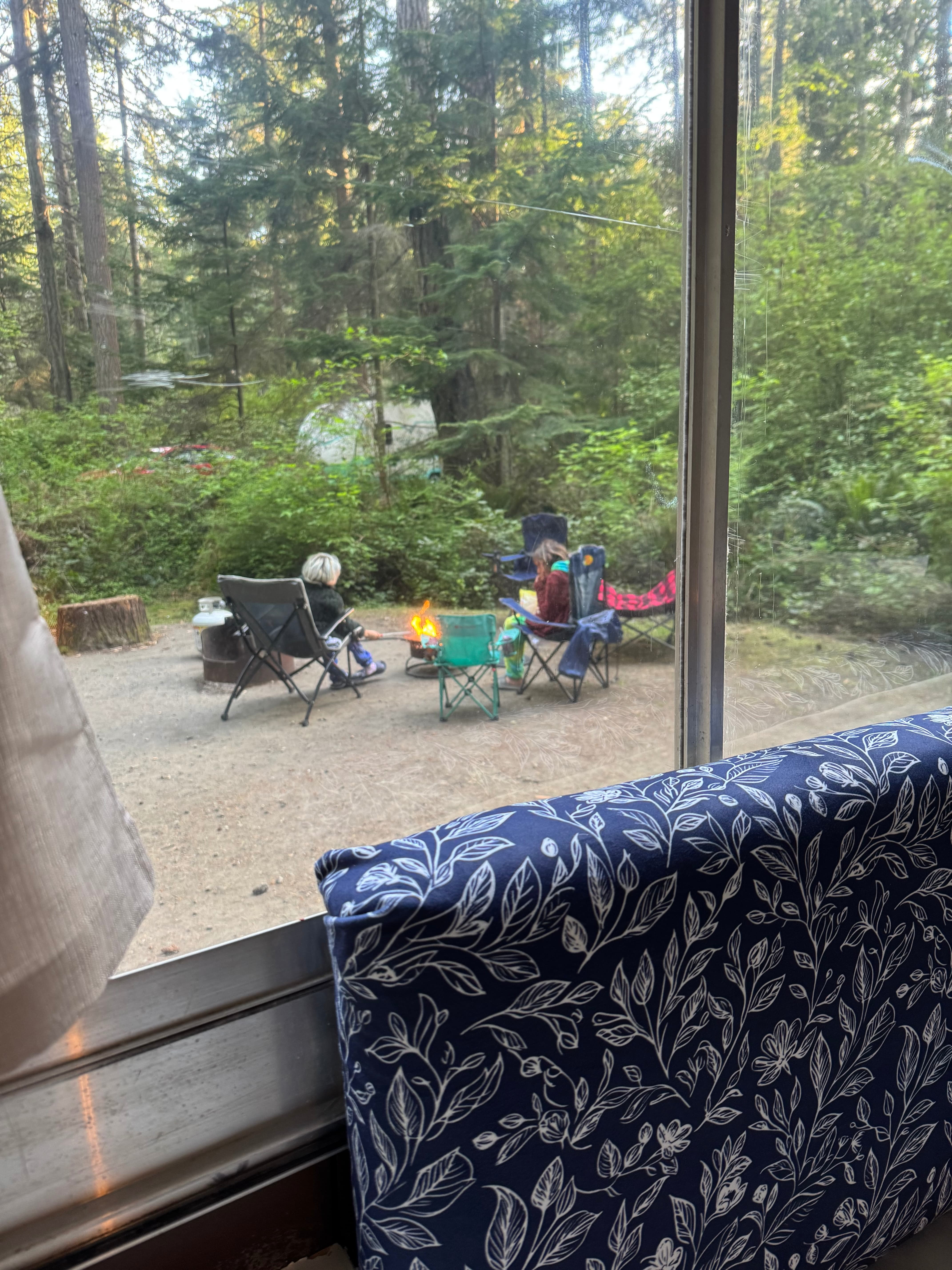 View from inside trailer of family around campfire