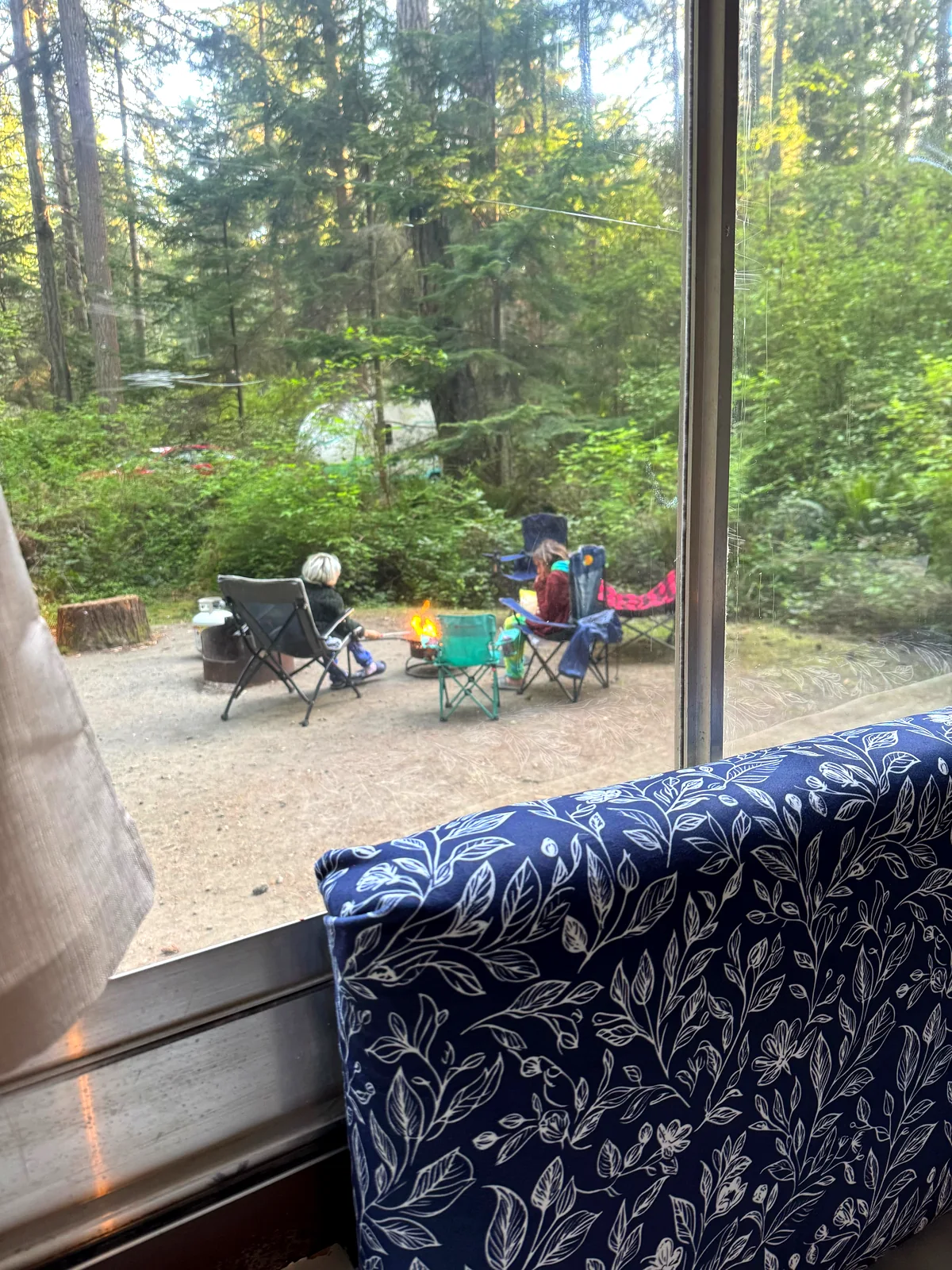 View from inside trailer of family around campfire